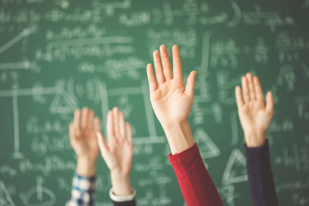 Students raised up hands green chalk board in classroom